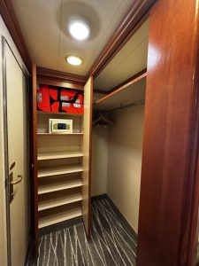 Cruise ship cabin storage showing walk-in closet, wall safe, and orange life preservers